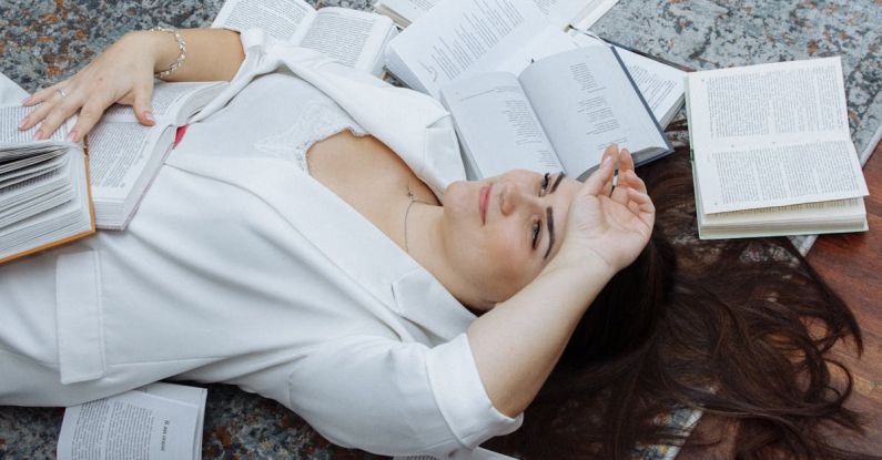 Learning Platforms - A woman laying on the floor with a pile of books